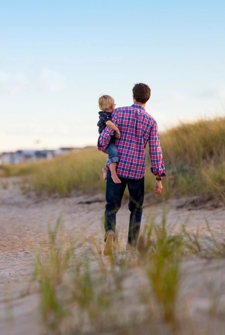 Father carrying his young child along a beach